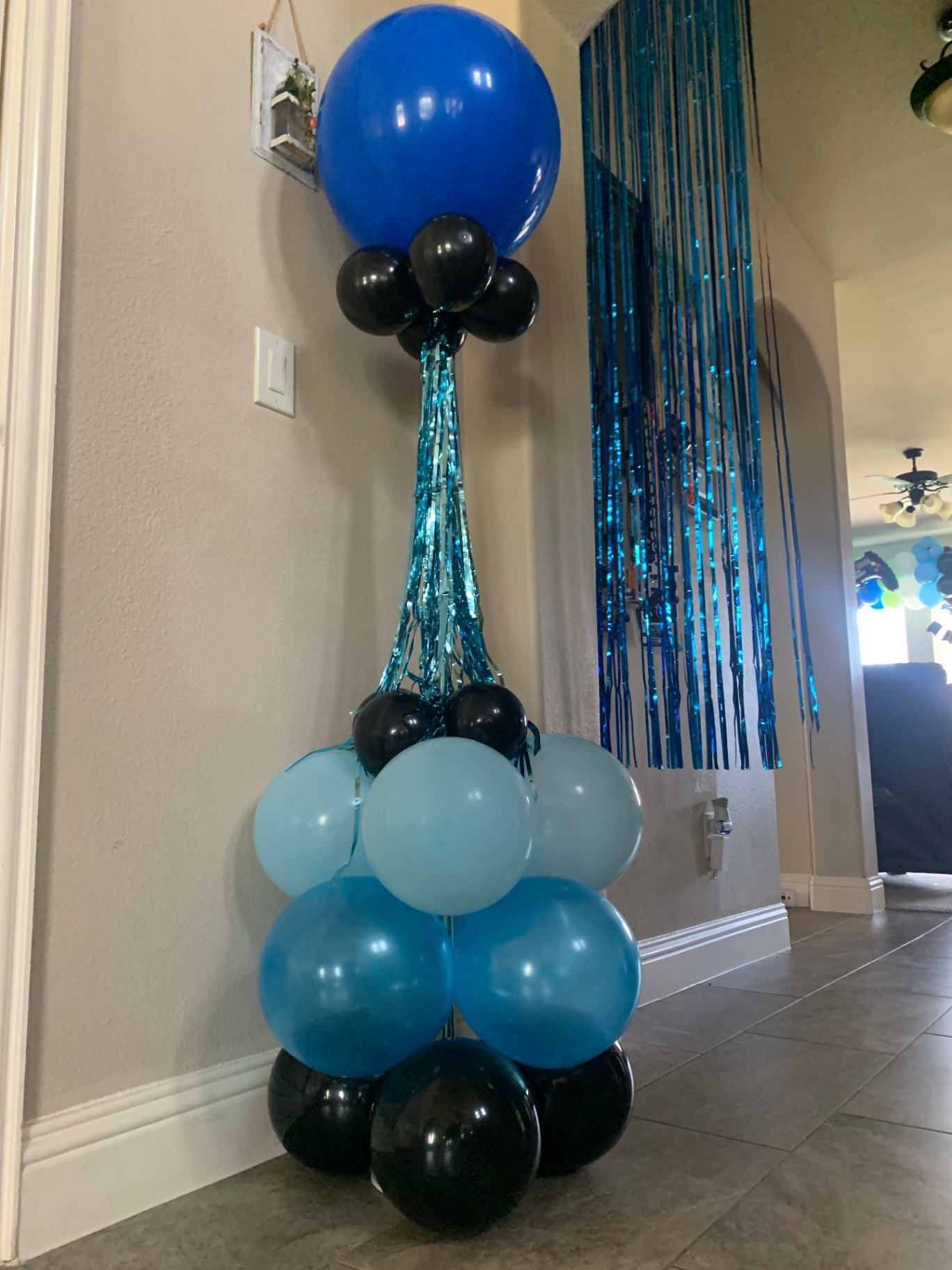 Blue and black balloon topiary tower with tinsel streamers