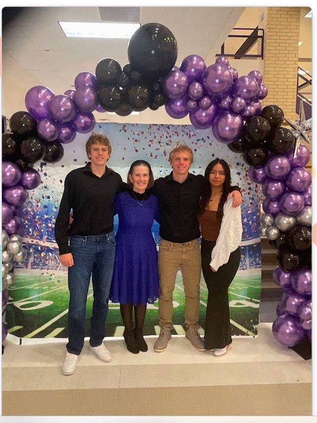 Purple and black organic balloon arch at football banquet with confetti backdrop