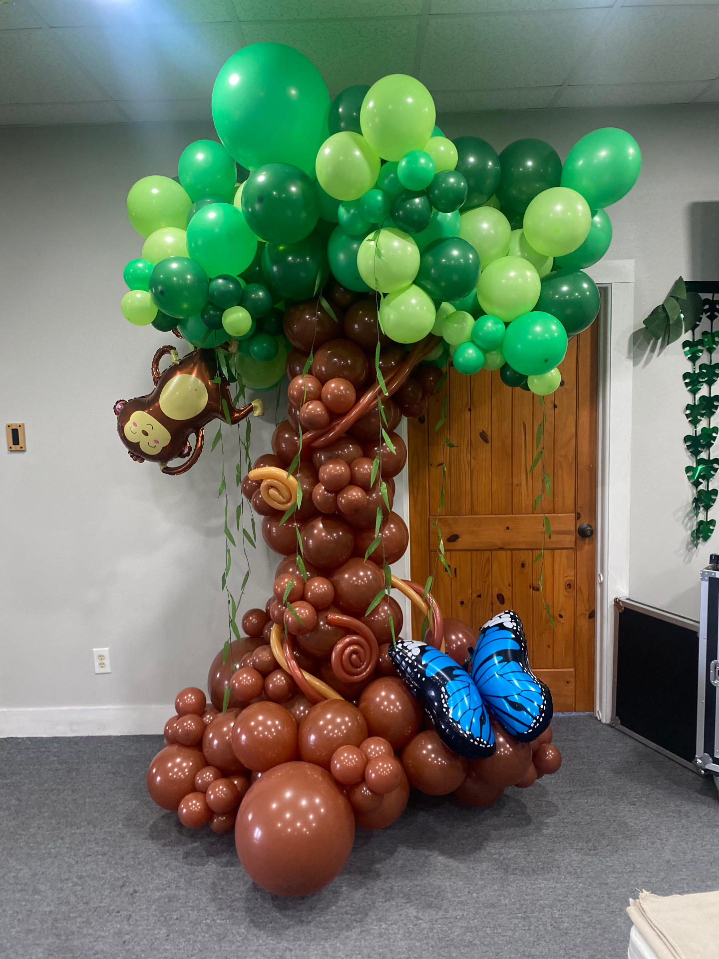 Jungle-themed balloon tree sculpture with green canopy, brown trunk, monkey and butterfly foils