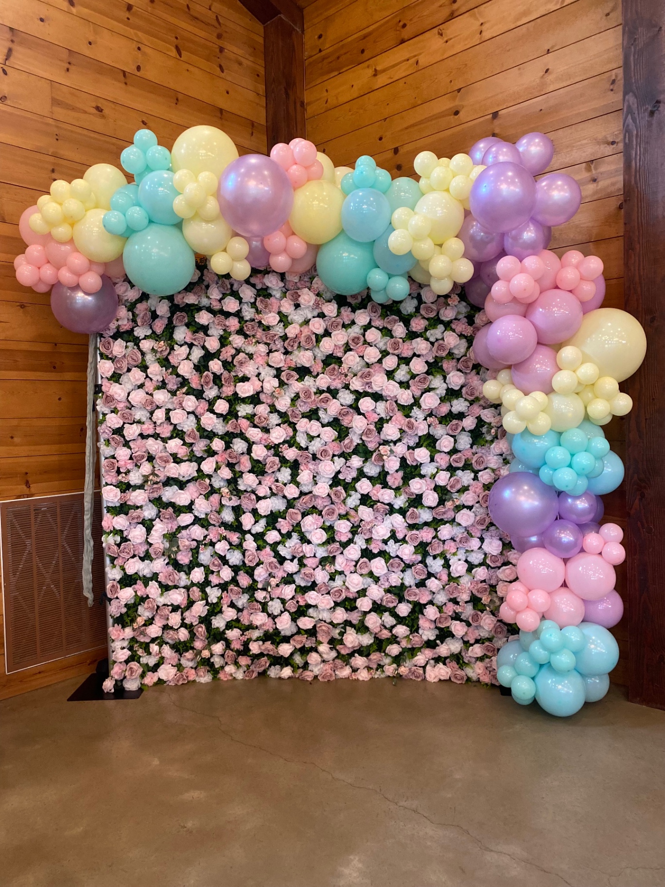 Pastel organic balloon garland framing a pink rose floral wall backdrop