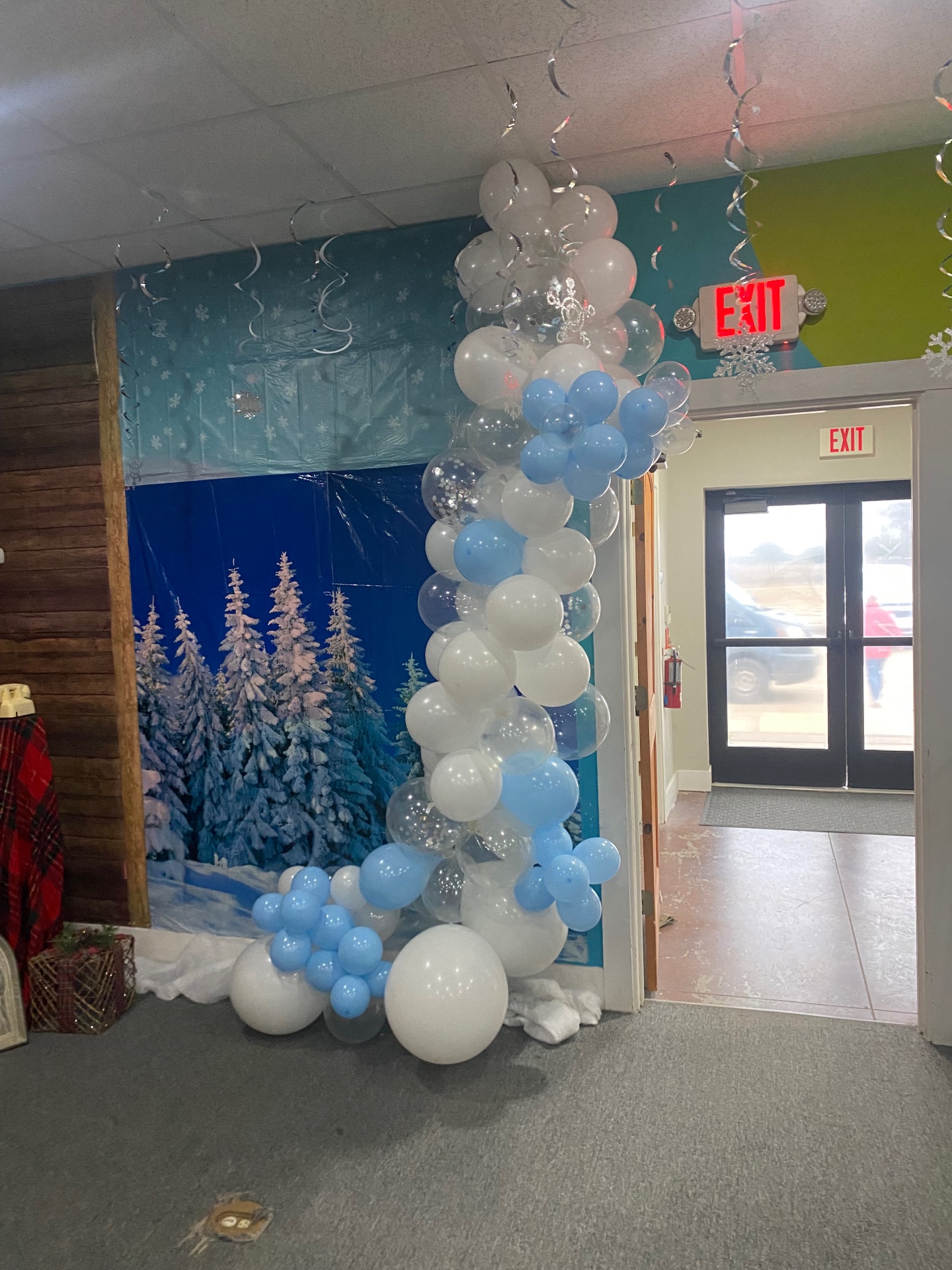 Winter wonderland balloon garland in white, blue, and clear over snowy forest backdrop