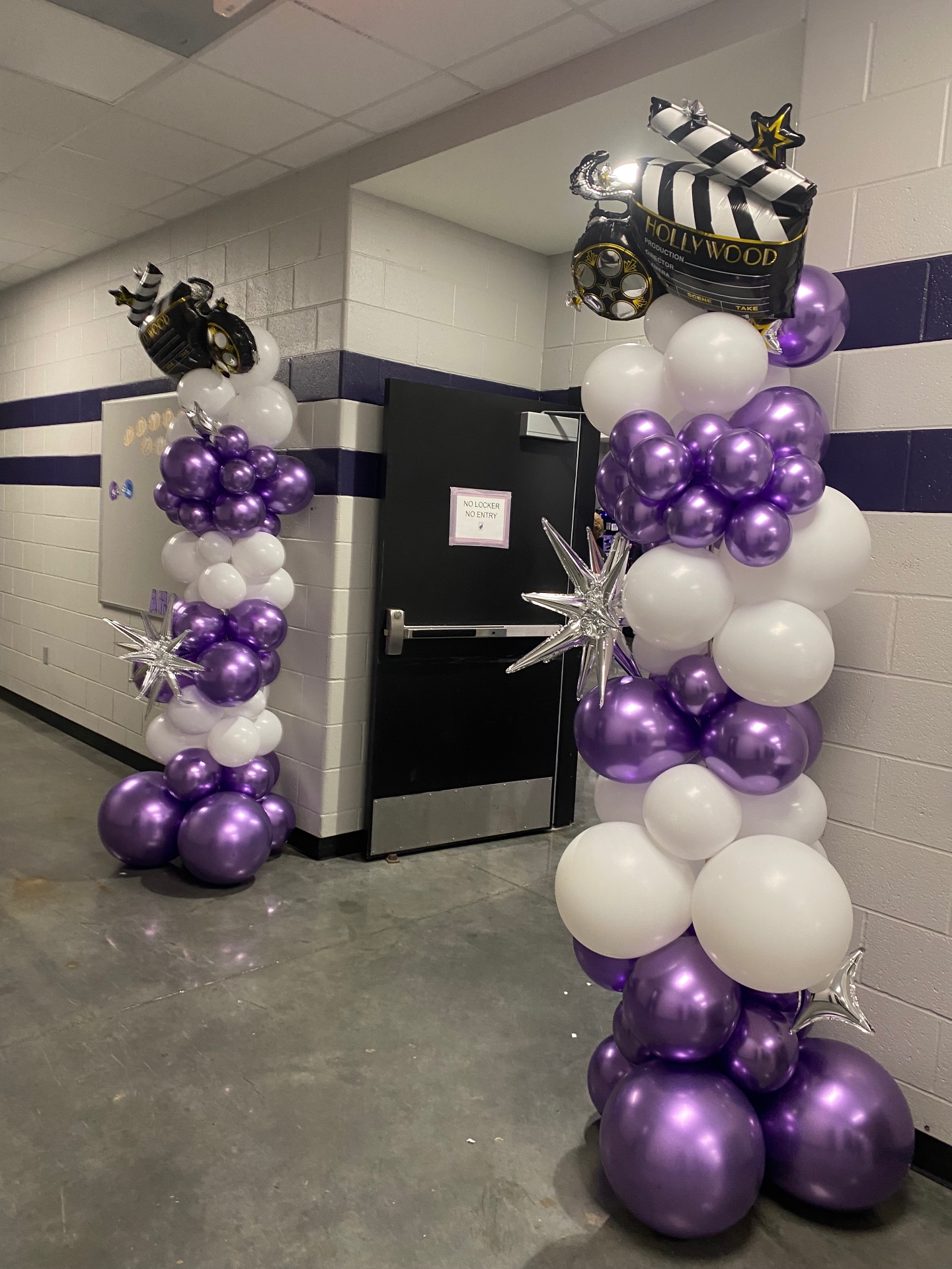 Pair of purple, white, and silver Hollywood-themed balloon columns with clapperboard toppers