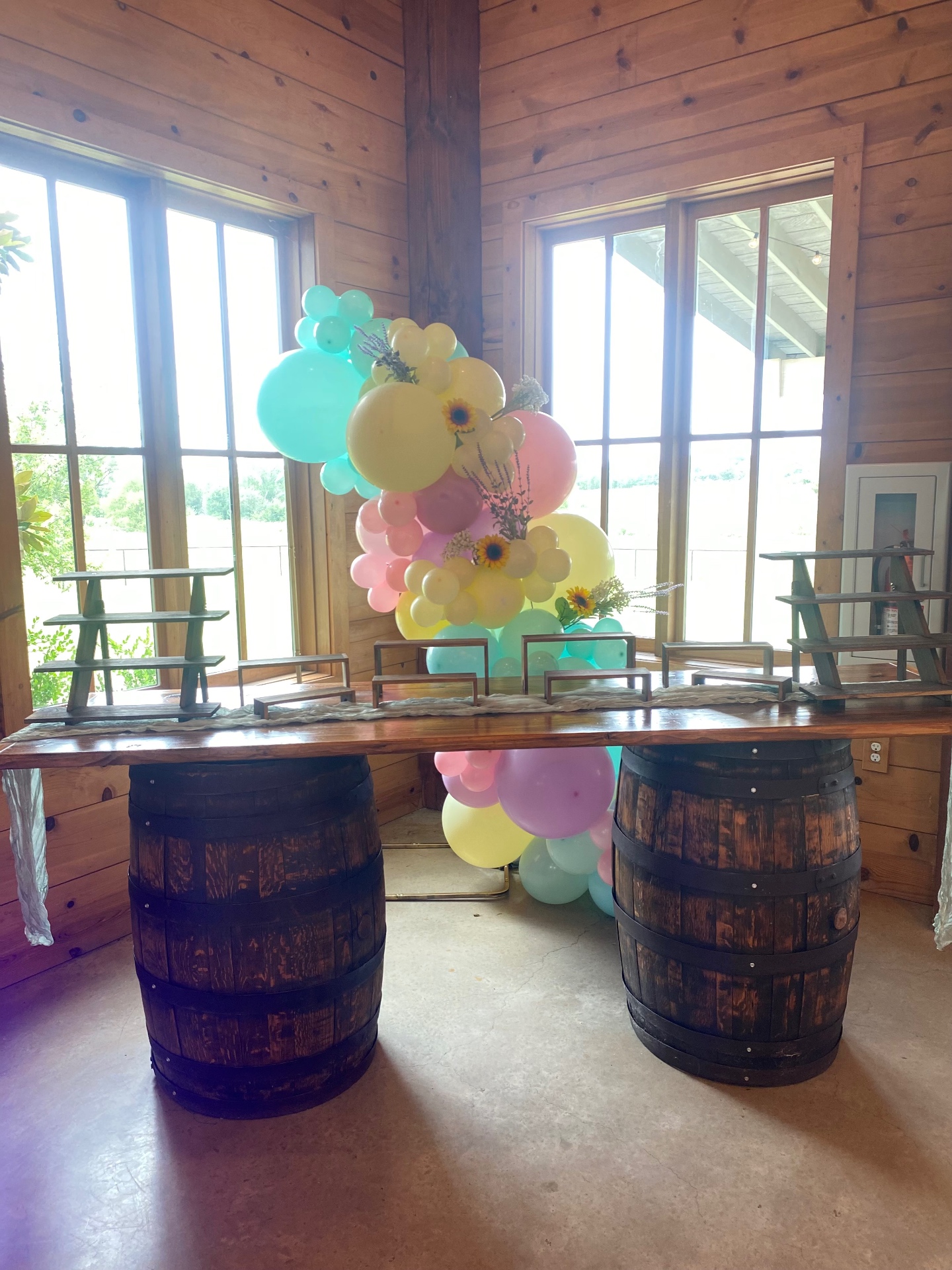 Pastel organic balloon garland accenting a rustic wood-and-barrel dessert display