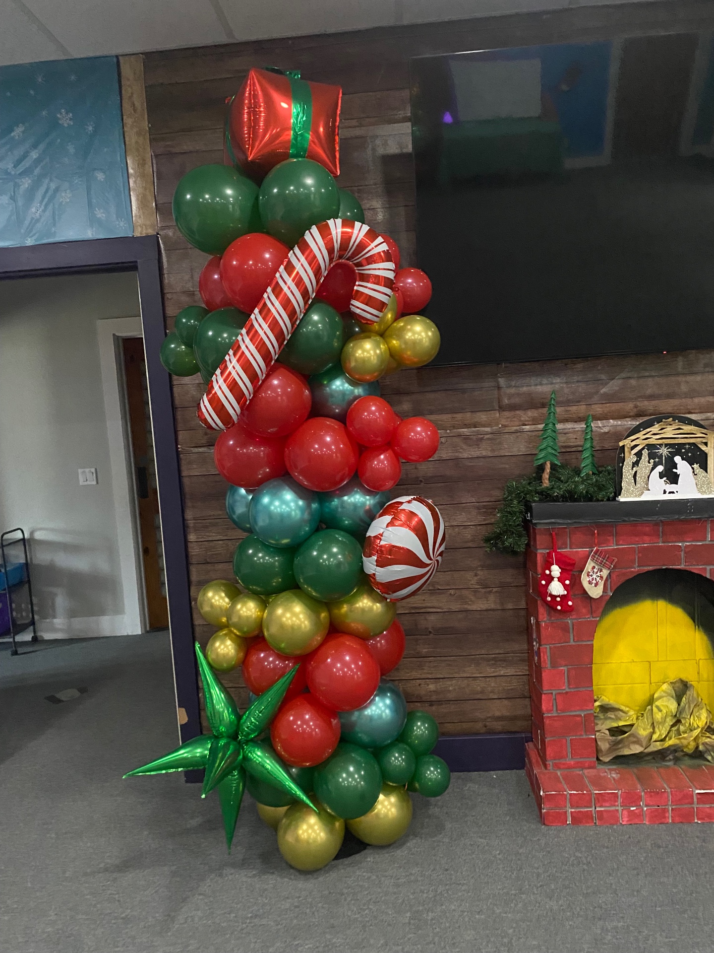 Christmas balloon column with candy cane, peppermint, and gift balloons in red, green, and gold